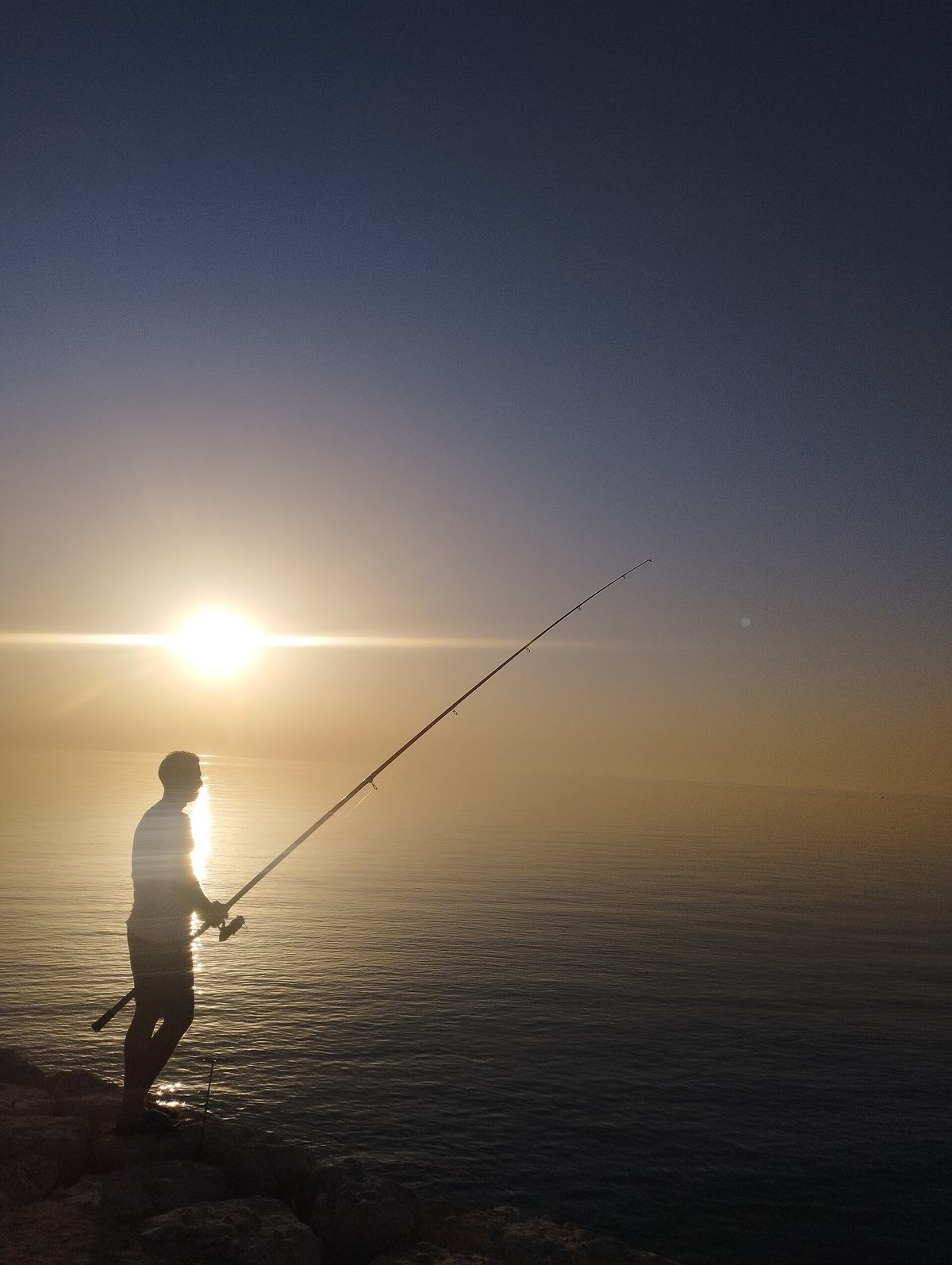 Khobar Corniche Seawalk — A man fishing on Al Khobar beach.jpg